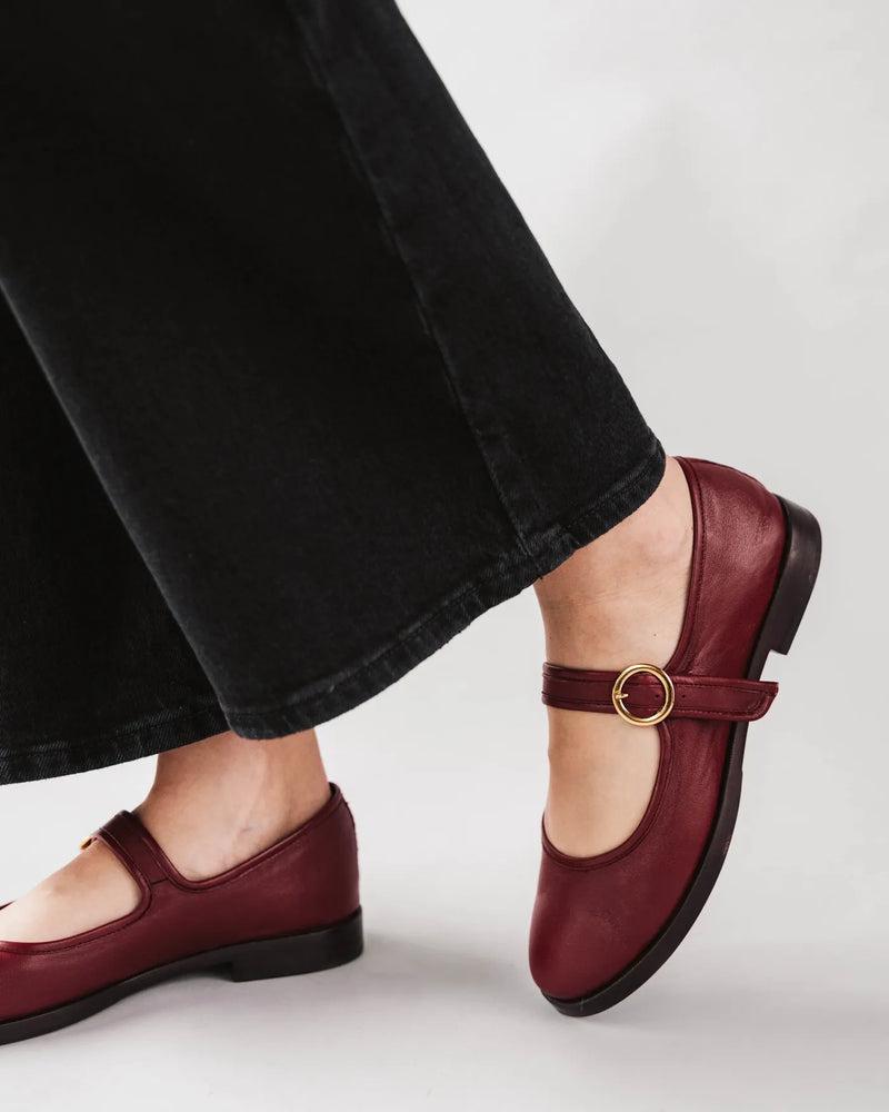 Woman wearing leather Mary Jane flats with gold circle buckle strap. The Today Mary Jane Resort Red. Sizes 5–12.