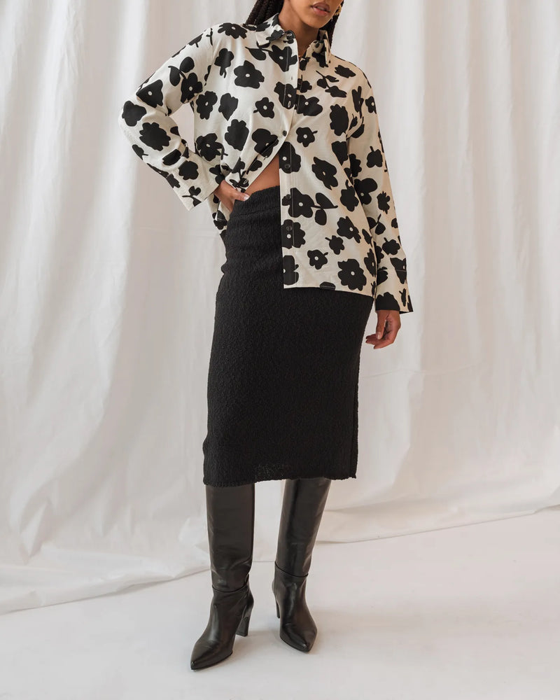 Woman in floral top and knit pencil skirt wearing leather tall boots. The Toujours Tall Boot Black. Sizes 5–12.
