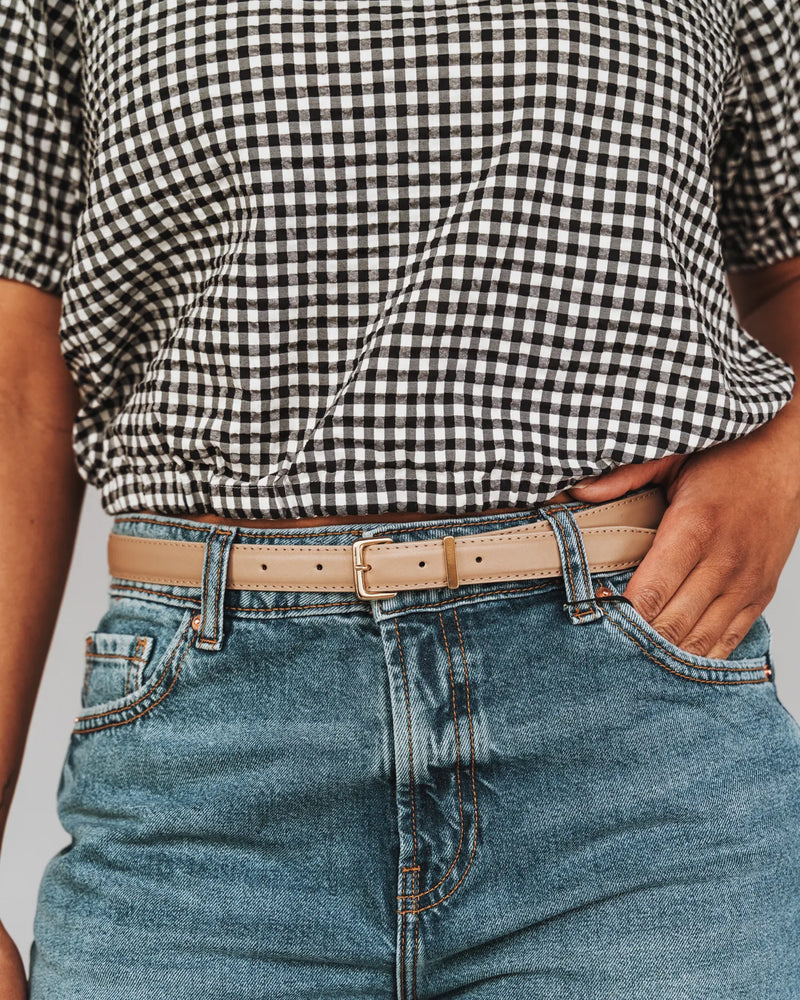 Woman wearing a biscotti leather trouser belt with gold hardware, styled with blue jeans. The Trouser Belt Gold Biscotti.