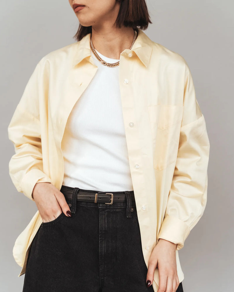 Woman wearing a black leather trouser belt with gold hardware, styled with dark jeans. The Trouser Belt Gold Black.