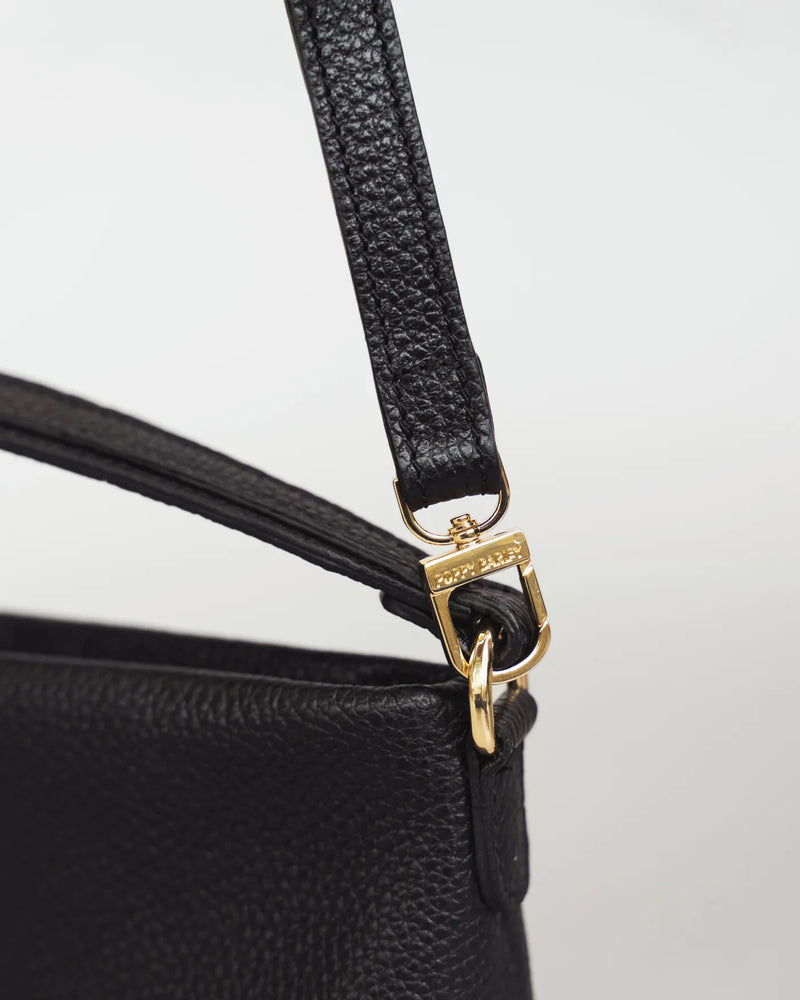 Close-up of the crossbody strap clip and gold Poppy Barley hardware on a leather mini bag. The Via Monte Bag Black.