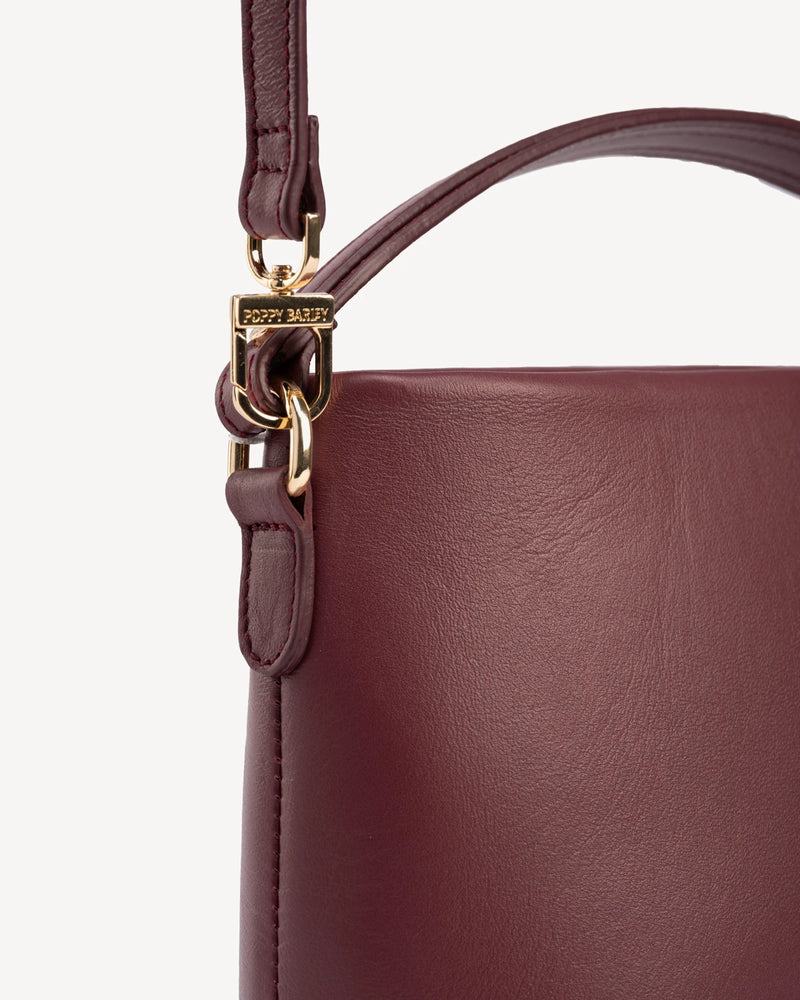 Close-up of gold-tone hardware and buckle strap detail. The Via Monte Bag Compote.