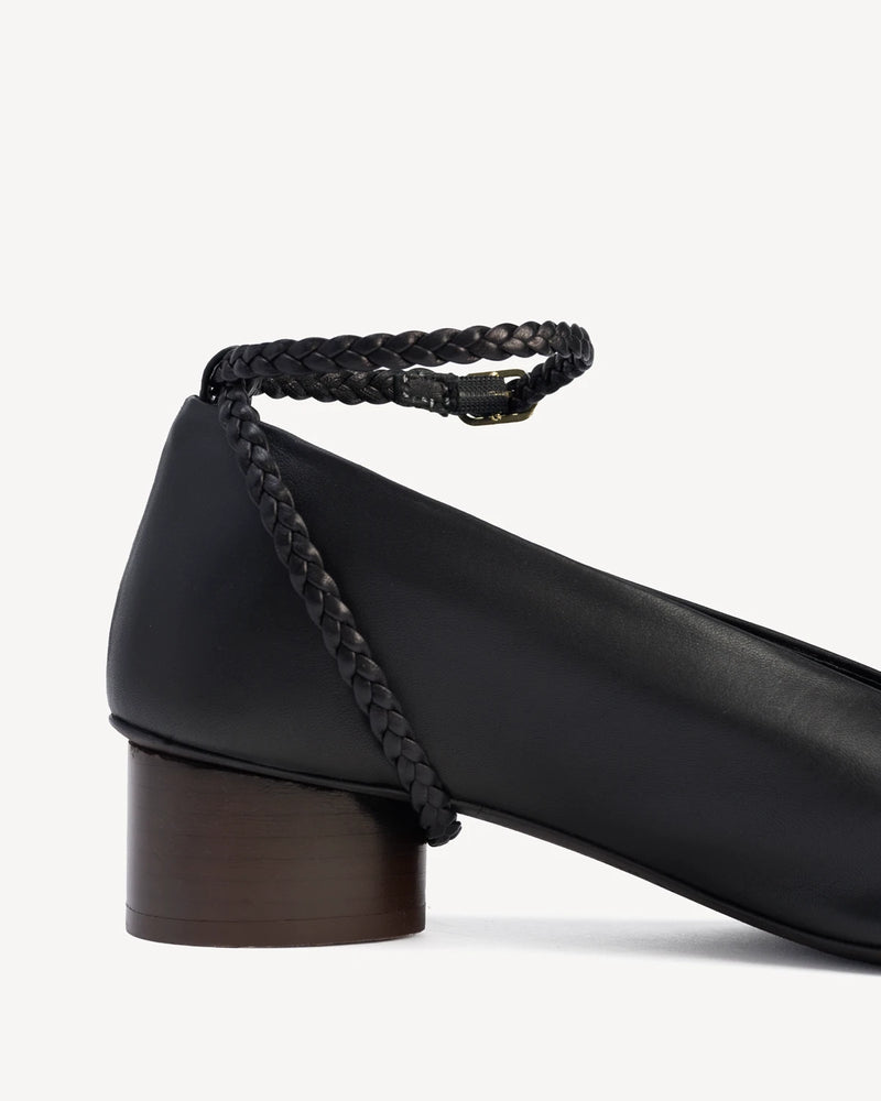 Close-up of the braided strap wrapping the block heel of a pump. The Alma Anklet Pump Black. Sizes 5–12.