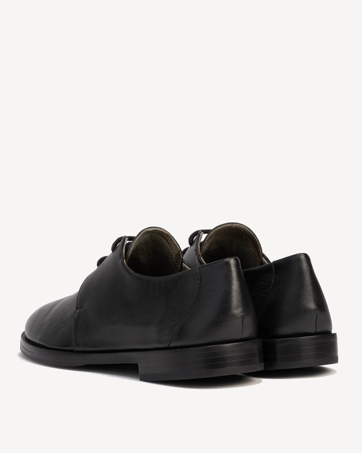 Back angle view of a pair of lace-up oxfords. The Capsule Oxford Black. Sizes 5–12, wide available.