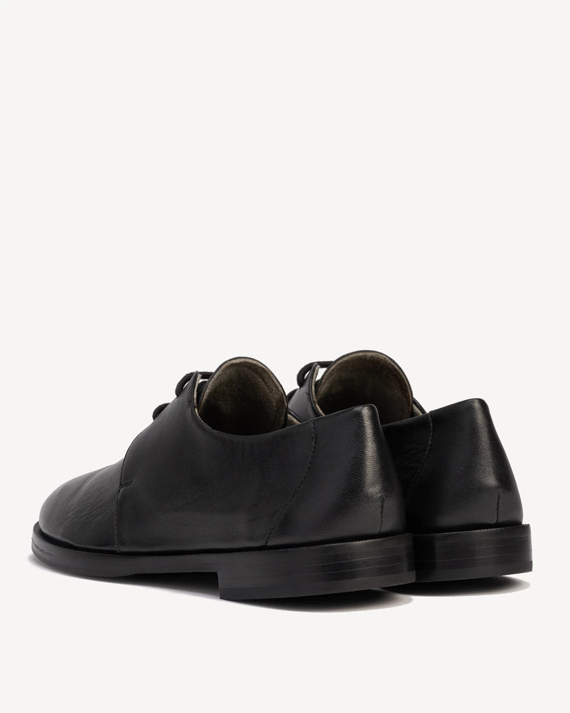 Back angle view of a pair of lace-up oxfords. The Capsule Oxford Black. Sizes 5–12, wide available.