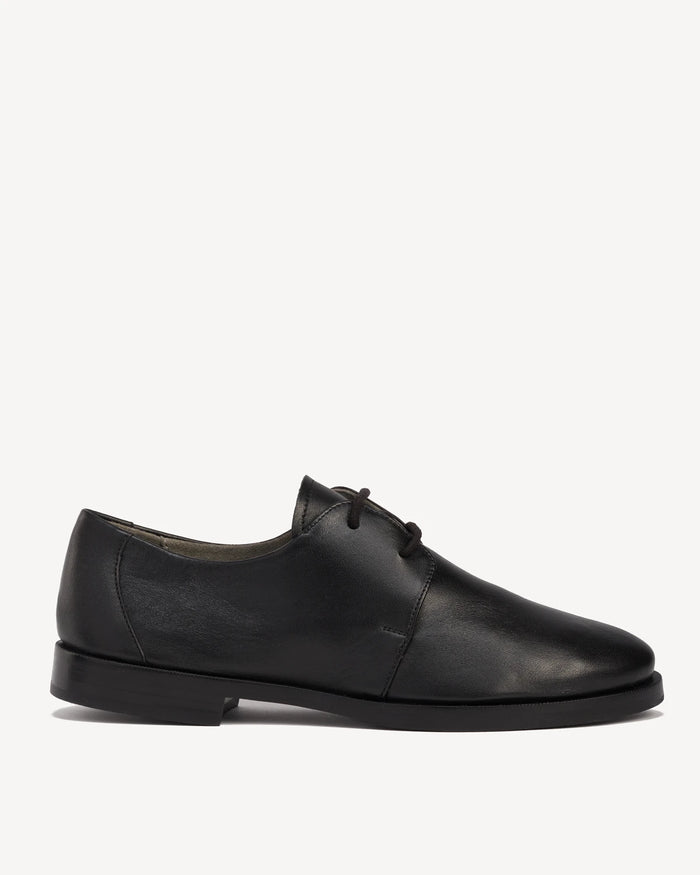 Side view of a leather lace-up oxford with a round toe. The Capsule Oxford Black. Sizes 5–12, wide available.
