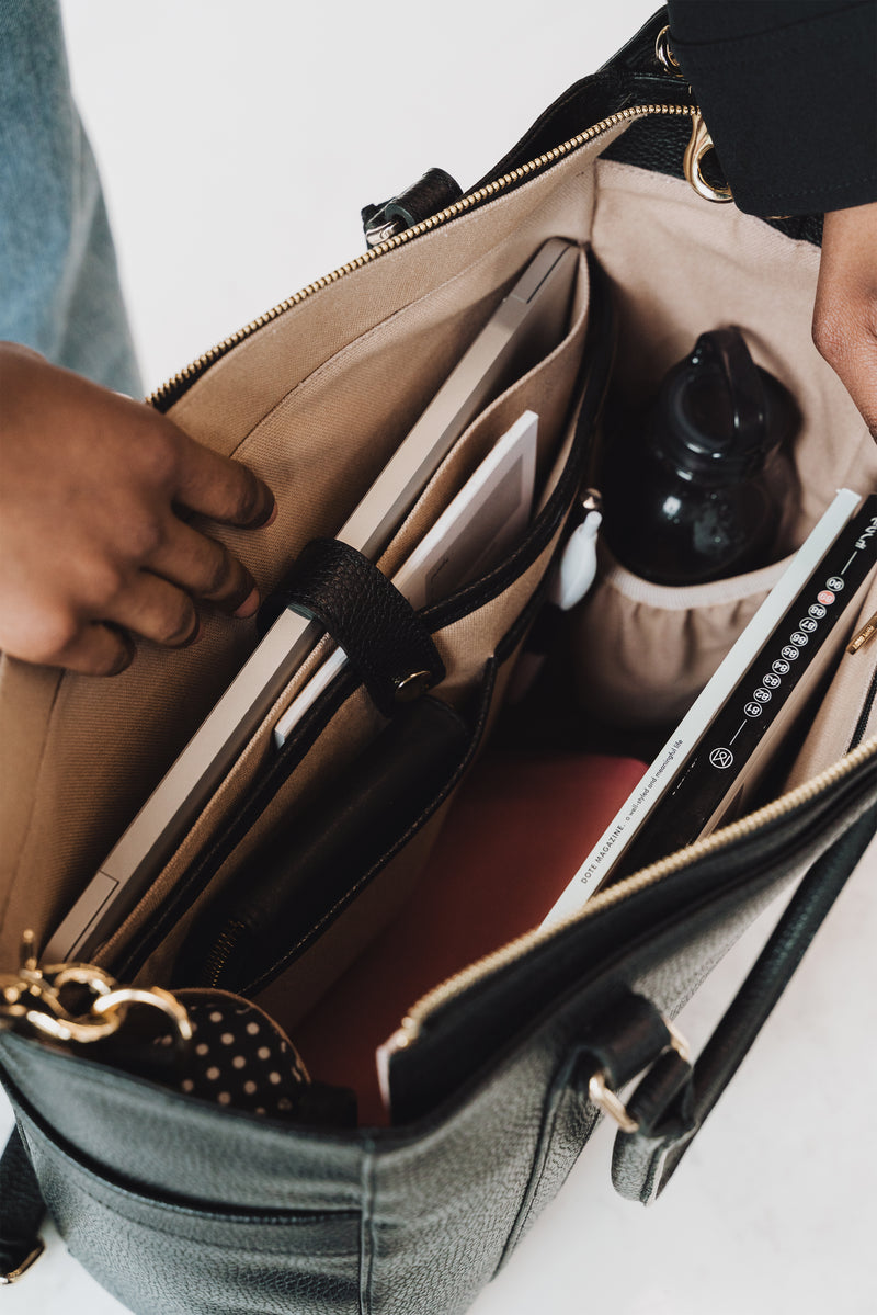 Interior view of the tote's organized pockets holding a tablet and accessories. The Colleague Tote Black.