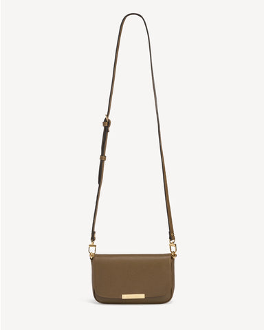 Front view of the leather flap bag with a long adjustable strap laid flat. The Day To Night Bag Tapenade.