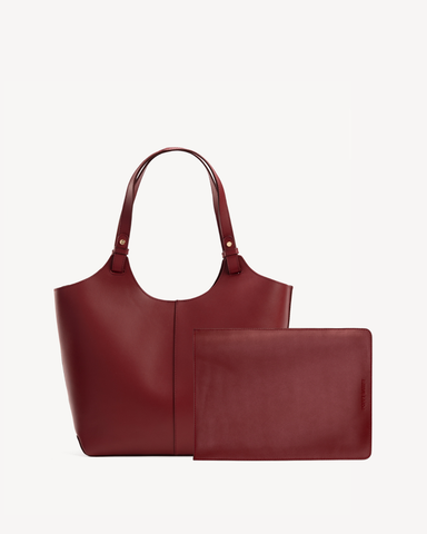 Product shot of a leather tote with tall handles beside a laptop sleeve. The Lisboa Tote + Laptop Sleeve Set Resort Red.