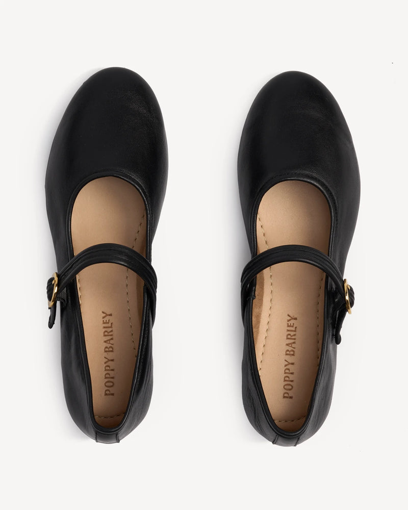 Overhead view of a pair of Mary Jane flats with buckled straps. The Modern-Day Mary Jane Blackout. Sizes 5–12.