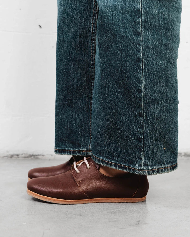 Close-up of a pebbled-leather oxford with wide-leg denim. The Eyelet Oxford 2.0 French Press. Sizes 5–12, wide available.