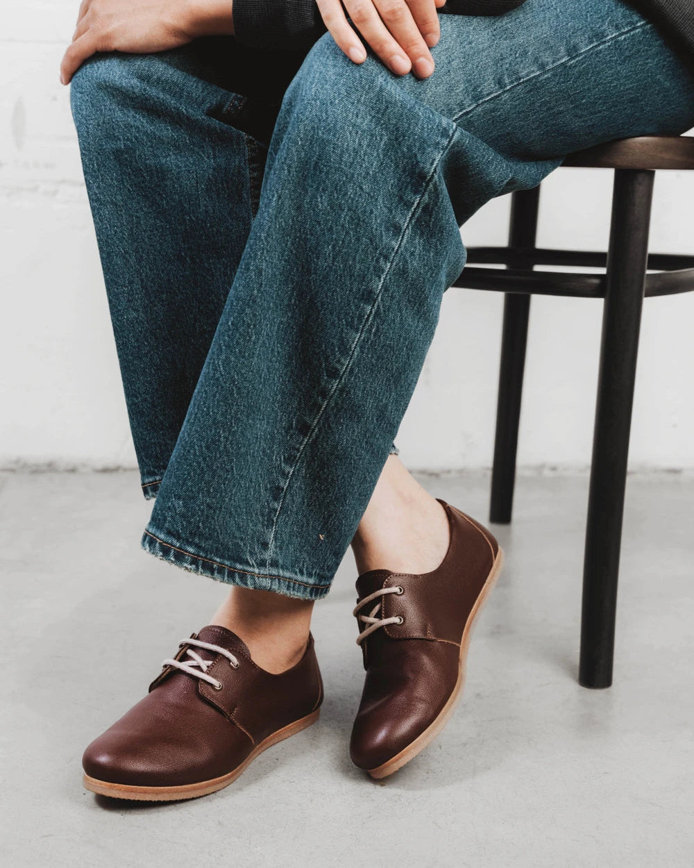 Person seated wearing pebbled-leather oxfords. The Eyelet Oxford 2.0 French Press. Sizes 5–12, wide available.