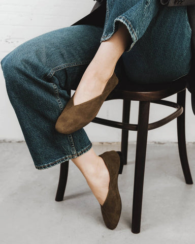 Side view of a suede flat with an asymmetrical V-cut topline. The Marché Flat Khaki Suede. Sizes 5–12.