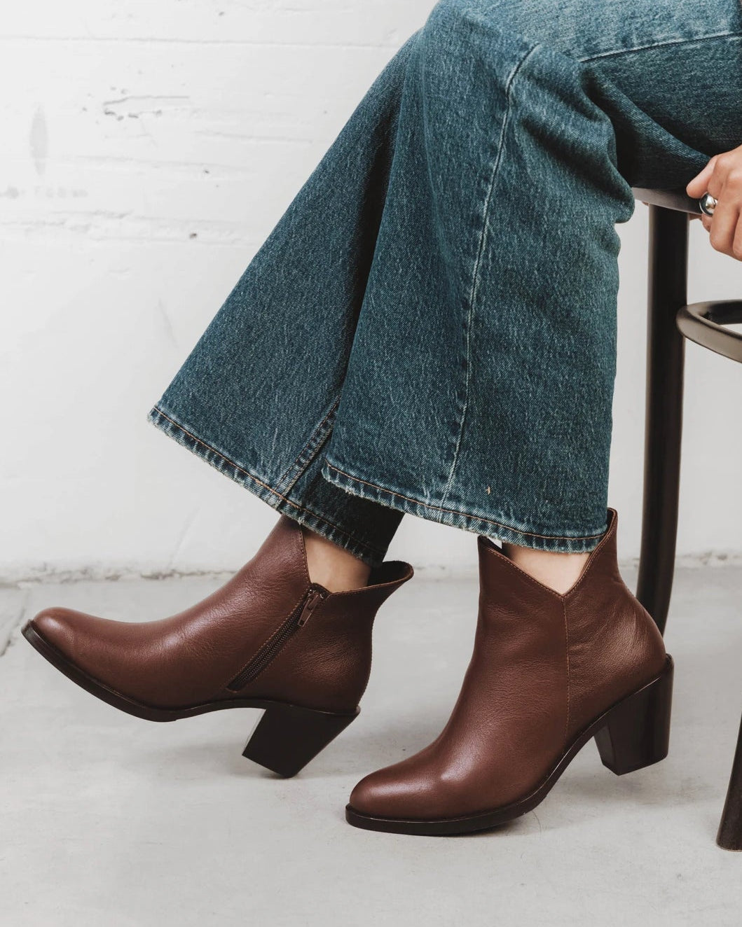 Person seated wearing pull-on ankle boots. The Two Point Five Ankle Boot French Press. Sizes 5–12, wide available.