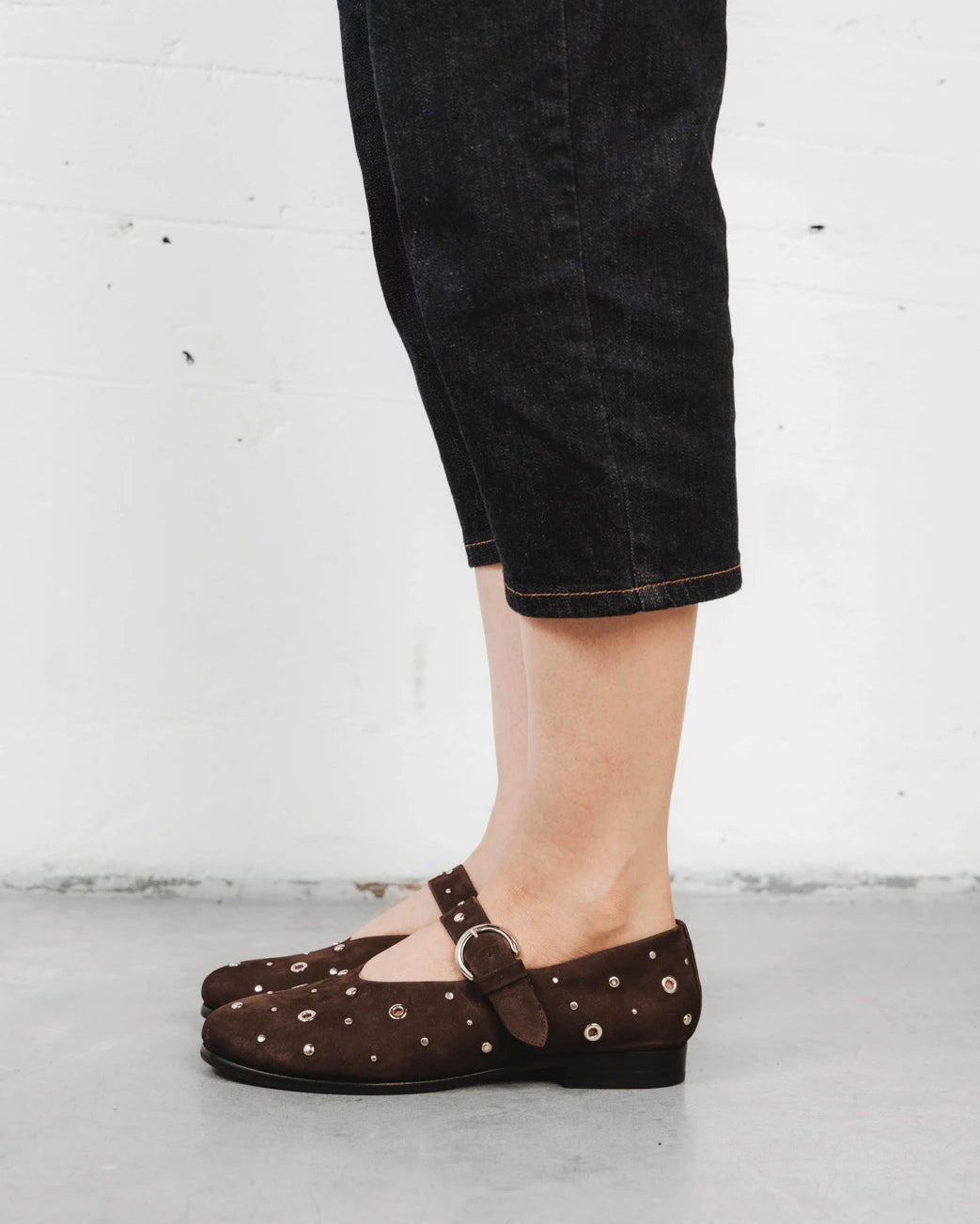 Close-up of a studded suede mary jane with cropped denim. The BLVD Mary Jane Cocoa Plum Studded. Sizes 5–12, wide available.