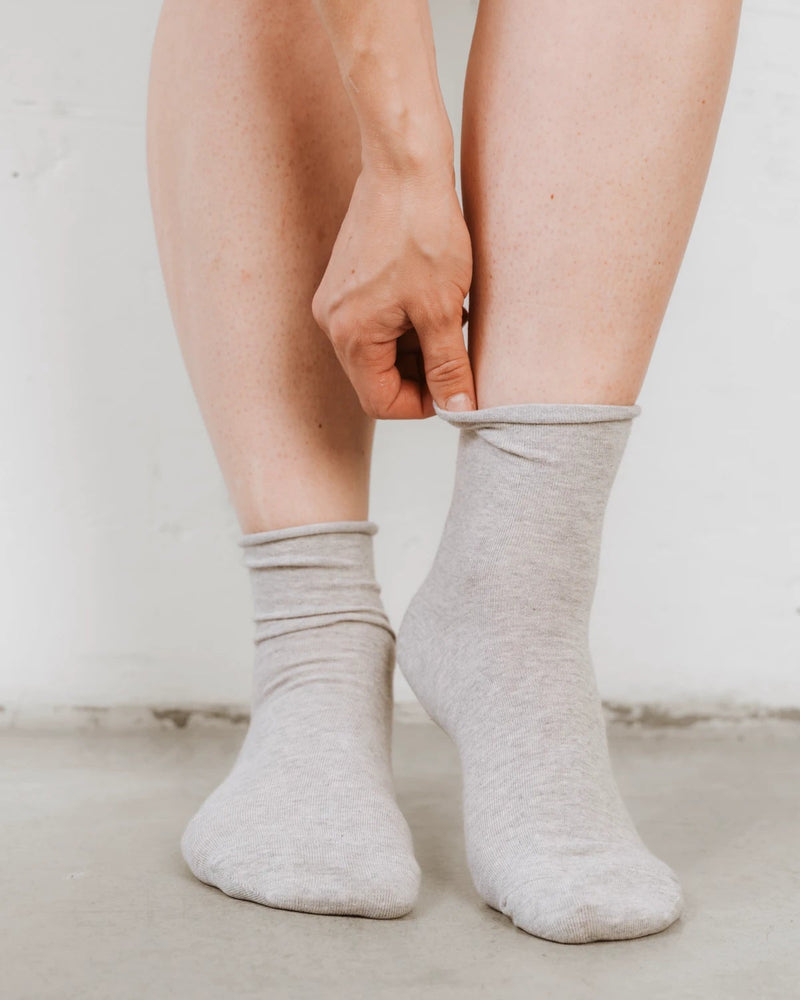 Side angle of ankle socks being adjusted at the ribbed cuff. The Daily Mid Crew Sock Grey Melange.