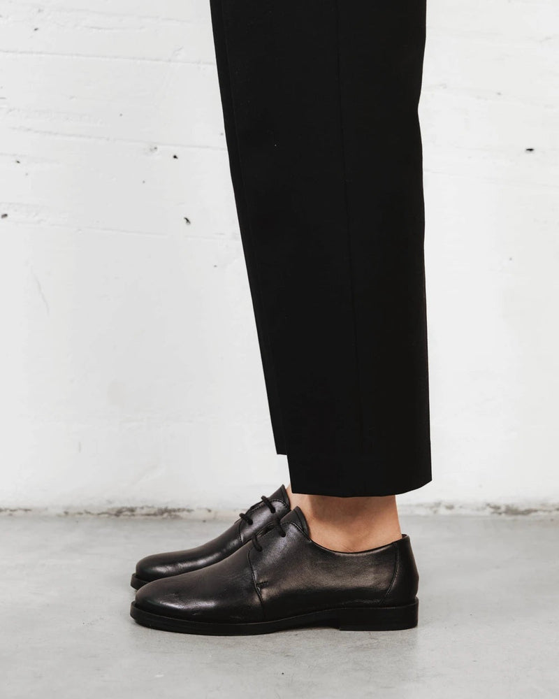 Full-length view of a model walking in the oxfords. The Capsule Oxford Black. Sizes 5–12, wide available.