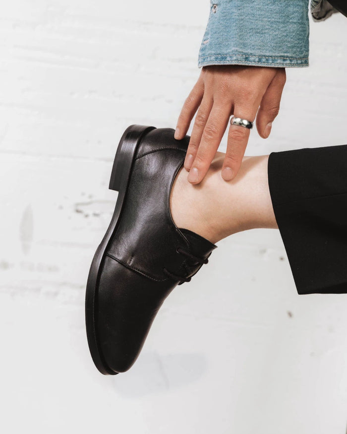 Side view of a leather lace-up oxford with a round toe. The Capsule Oxford Black. Sizes 5–12, wide available.