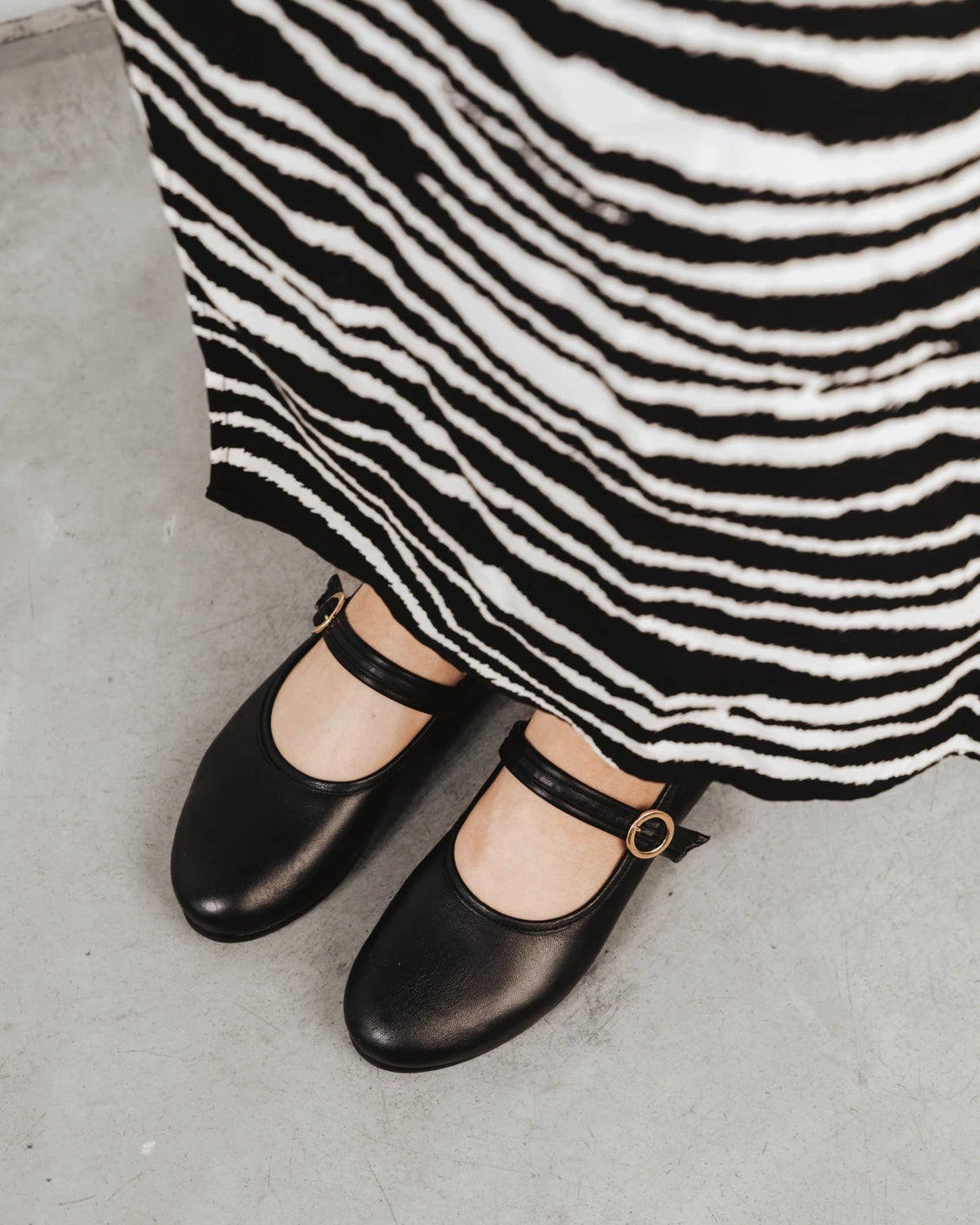 Close-up of the Mary Jane flats worn with a zebra-print dress. The Modern-Day Mary Jane Blackout. Sizes 5–12.