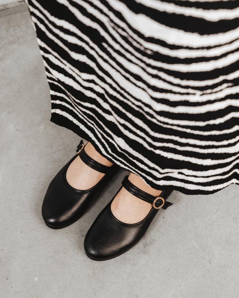 Close-up of the Mary Jane flats worn with a zebra-print dress. The Modern-Day Mary Jane Blackout. Sizes 5–12.