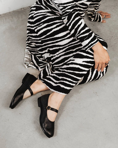 Side view of a leather Mary Jane flat with round toe and ankle strap. The Modern-Day Mary Jane Blackout. Sizes 5–12.