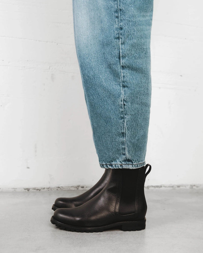 Model wearing the Chelsea boots with jeans. The On Tread Chelsea Boot Black Water Resistant. Sizes 5–12, wide available.
