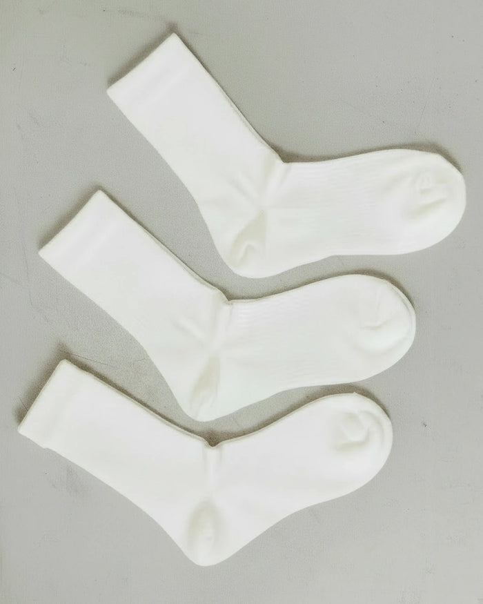 Flat lay of three pairs from the set, showing ribbed knit cuffs. The Dressy Crew Sock Alabaster 3-Pack.
