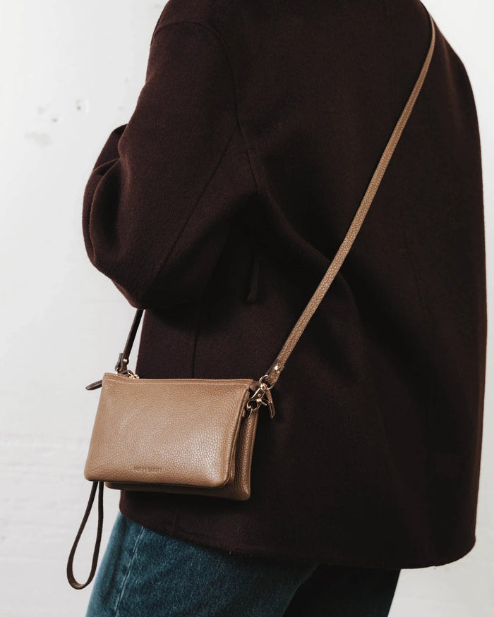 Front view of the pebbled-leather wristlet with a long crossbody strap laid flat. The 3-in-1 Wristlet Tapenade.