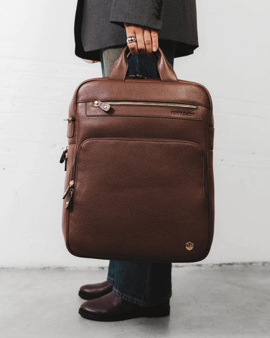Front view of the pebbled-leather backpack with top handle and zip pockets. The Backpack French Press.