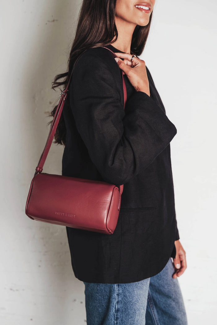 Cylindrical barrel bag with long adjustable crossbody strap. The Annex Bag Compote.