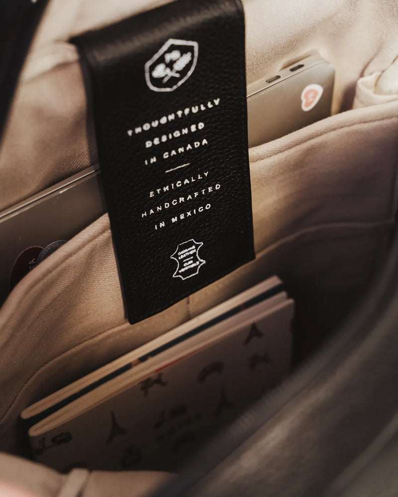 Interior view of the leather brand tag inside the backpack's lined pocket. The Backpack Black / Black Nubuck.