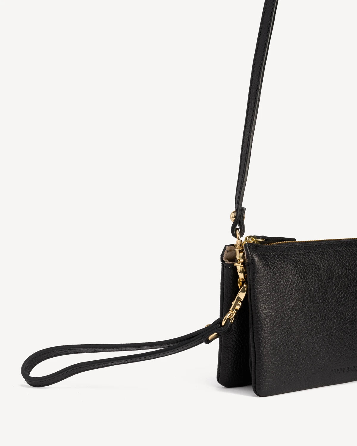 Close-up of the gold zipper pull and wrist strap on the pebbled-leather wristlet. The 3-in-1 Wristlet Black.